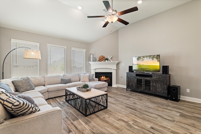 living room with hardwood / wood-style flooring, ceiling fan, and vaulted ceiling