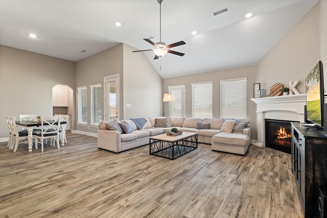 living room featuring light hardwood / wood-style floors, high vaulted ceiling, and ceiling fan