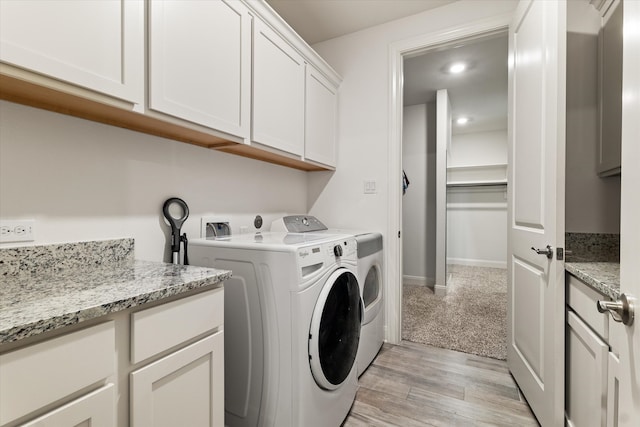 washroom with washer and dryer, light hardwood / wood-style floors, and cabinets