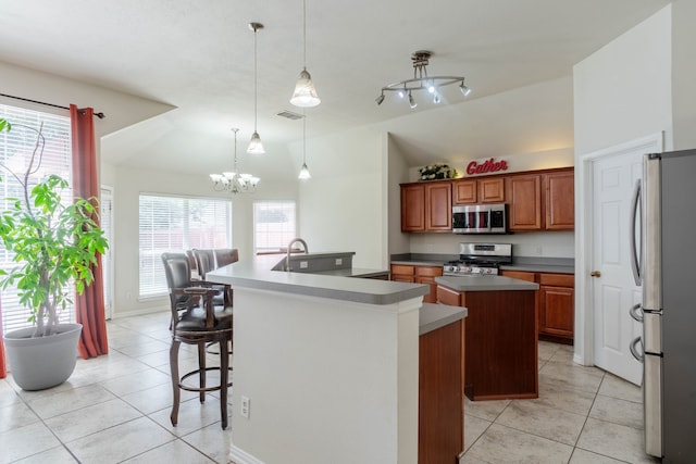 kitchen with an inviting chandelier, decorative light fixtures, an island with sink, stainless steel appliances, and light tile patterned flooring