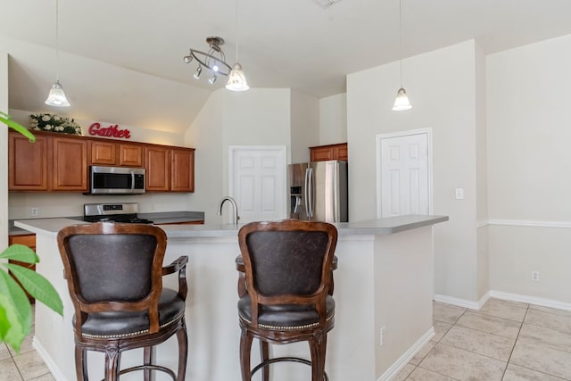 kitchen featuring a breakfast bar area, pendant lighting, light tile patterned floors, stainless steel appliances, and lofted ceiling