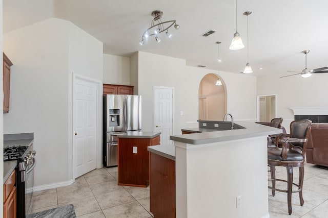 kitchen featuring stainless steel appliances, an island with sink, light tile patterned flooring, ceiling fan, and pendant lighting