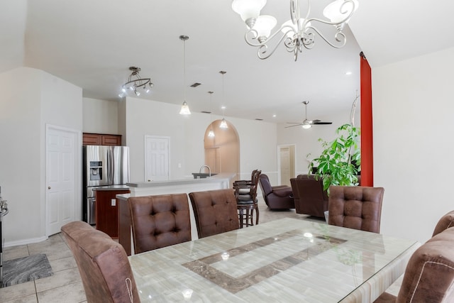 tiled dining space featuring lofted ceiling, sink, and ceiling fan with notable chandelier