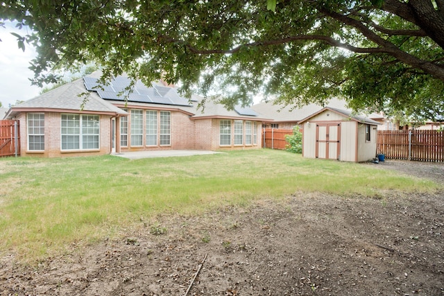 back of property with a yard, a patio, and a storage unit