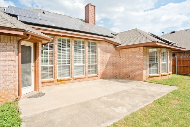 rear view of property featuring solar panels and a patio