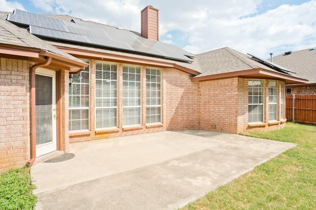 7525 Juliet Ln, Fort Worth, TX 76137 - rear view of property with roof mounted solar panels, brick siding, a chimney, and a patio area