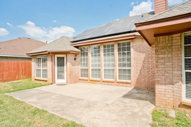 7525 Juliet Ln, Fort Worth, TX 76137 - rear view of house featuring roof mounted solar panels, a patio, a chimney, fence, and brick siding