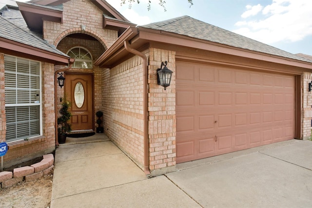 7525 Juliet Ln, Fort Worth, TX 76137 - entrance to property featuring roof with shingles, concrete driveway, an attached garage, and brick siding