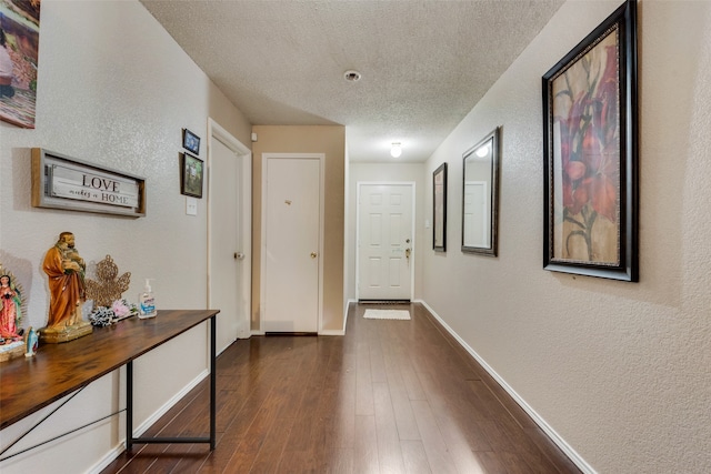 hallway with dark wood-type flooring and a textured ceiling