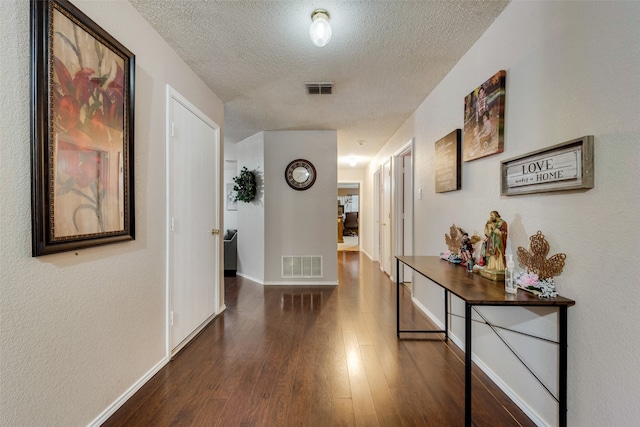 corridor featuring a textured ceiling and dark hardwood / wood-style flooring