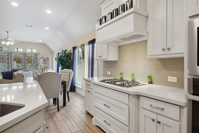 kitchen with vaulted ceiling, a healthy amount of sunlight, stainless steel gas stovetop, and ceiling fan