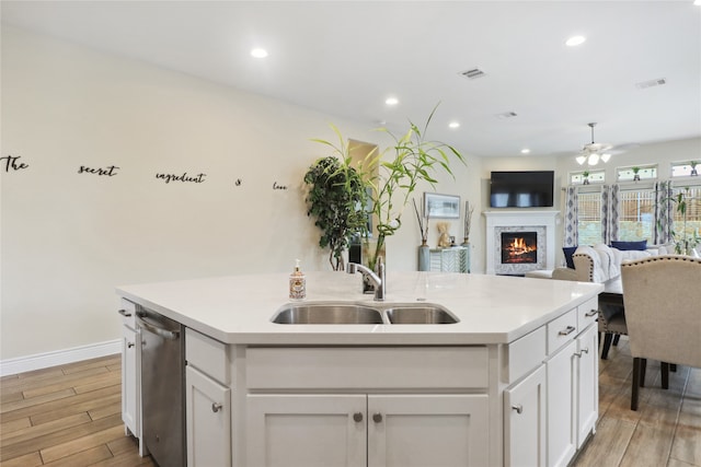 kitchen featuring a kitchen island with sink, light wood-type flooring, sink, and ceiling fan