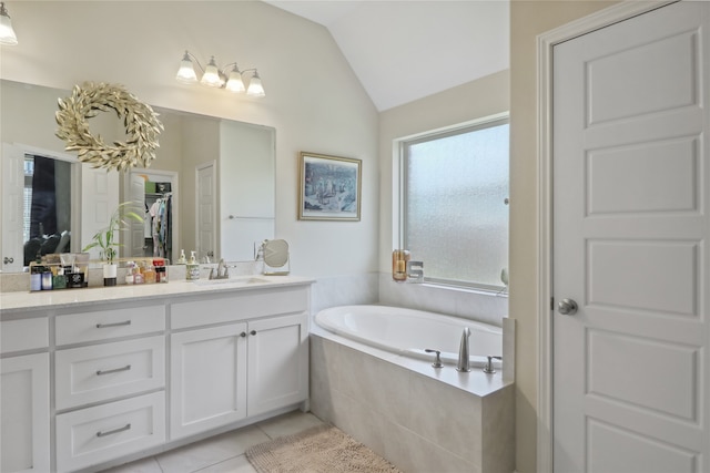 bathroom featuring tile patterned floors, vaulted ceiling, tiled bath, and vanity