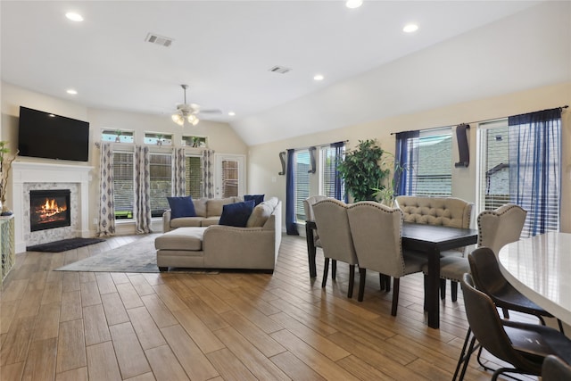 living room with plenty of natural light, ceiling fan, light hardwood / wood-style flooring, and vaulted ceiling