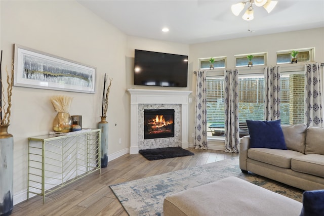 living room featuring ceiling fan, a tile fireplace, and light hardwood / wood-style floors