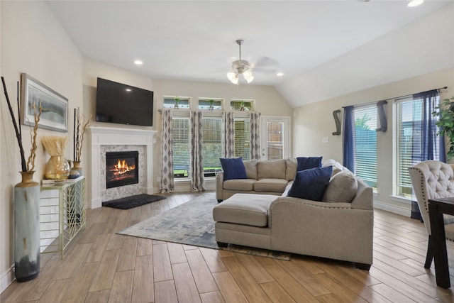 living room featuring plenty of natural light, a premium fireplace, vaulted ceiling, and ceiling fan