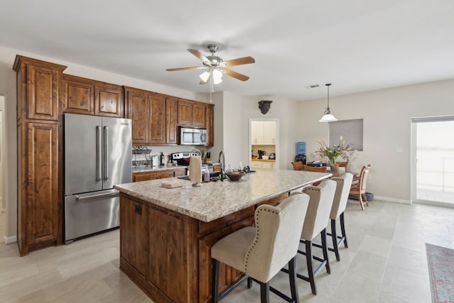 kitchen featuring decorative light fixtures, light stone counters, sink, ceiling fan, and appliances with stainless steel finishes