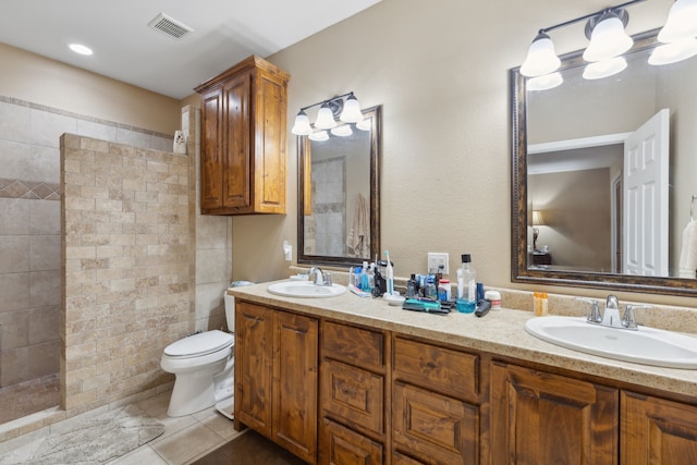 bathroom featuring tiled shower, tile patterned flooring, toilet, and vanity