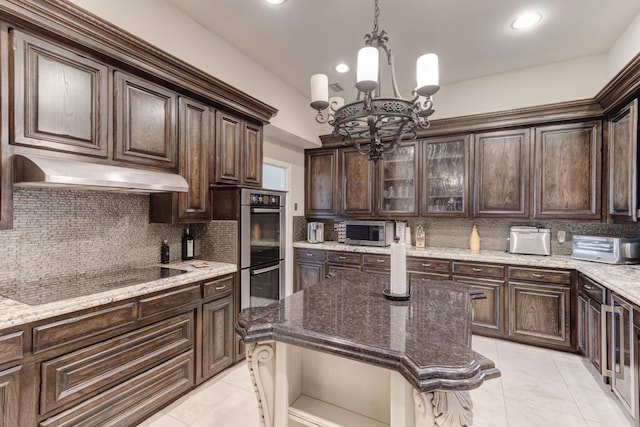 kitchen with tasteful backsplash, dark brown cabinets, appliances with stainless steel finishes, a center island, and an inviting chandelier