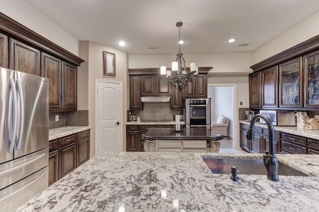 kitchen featuring appliances with stainless steel finishes, decorative backsplash, dark brown cabinets, and pendant lighting