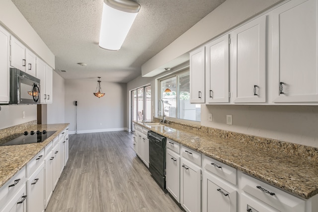 kitchen with light wood-type flooring, light stone countertops, white cabinetry, sink, and black appliances