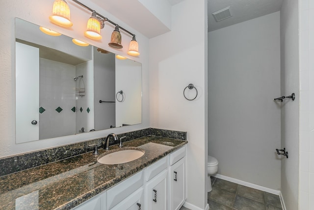 bathroom featuring vanity, toilet, tiled shower, and tile patterned flooring