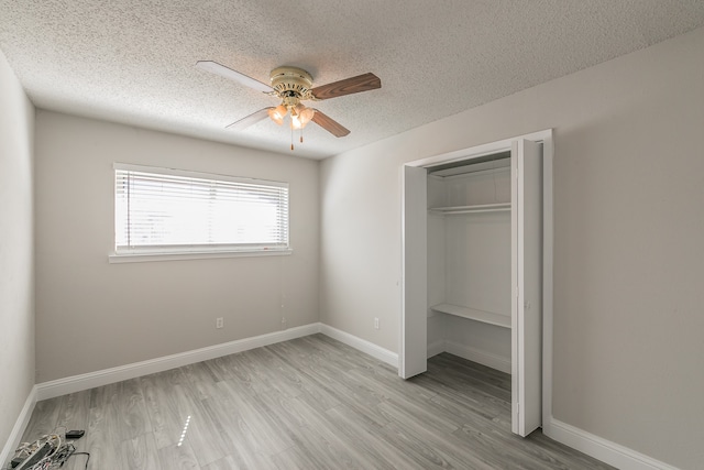 unfurnished bedroom with light hardwood / wood-style floors, a textured ceiling, ceiling fan, and a closet