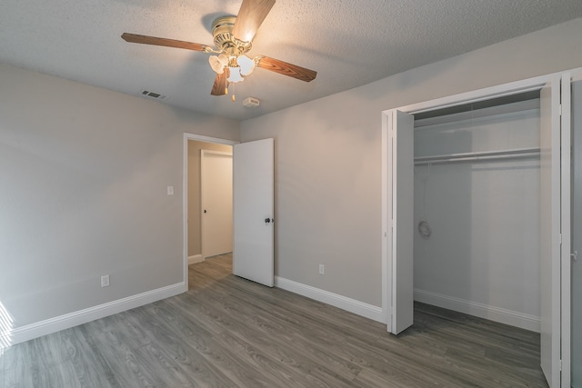 unfurnished bedroom with a closet, ceiling fan, dark hardwood / wood-style flooring, and a textured ceiling