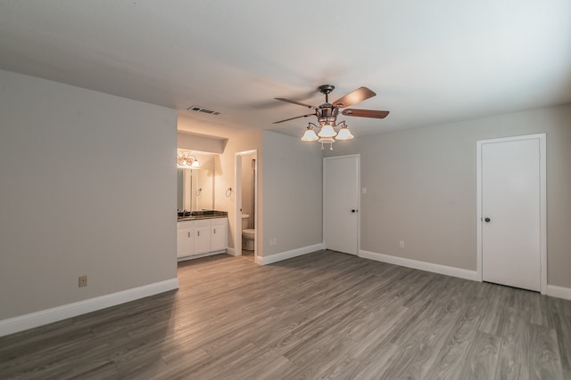 unfurnished bedroom featuring ensuite bath, hardwood / wood-style flooring, ceiling fan, and a closet