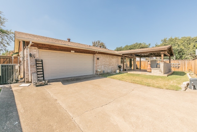 ranch-style home featuring a garage, a front lawn, an outbuilding, and central air condition unit