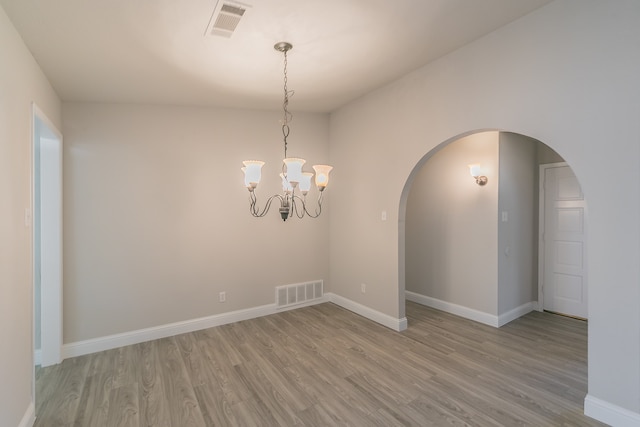 unfurnished room with light wood-type flooring and a chandelier