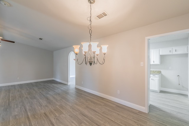 unfurnished dining area with hardwood / wood-style floors and ceiling fan with notable chandelier