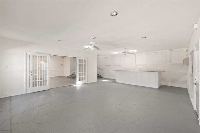 unfurnished living room with brick wall and ceiling fan