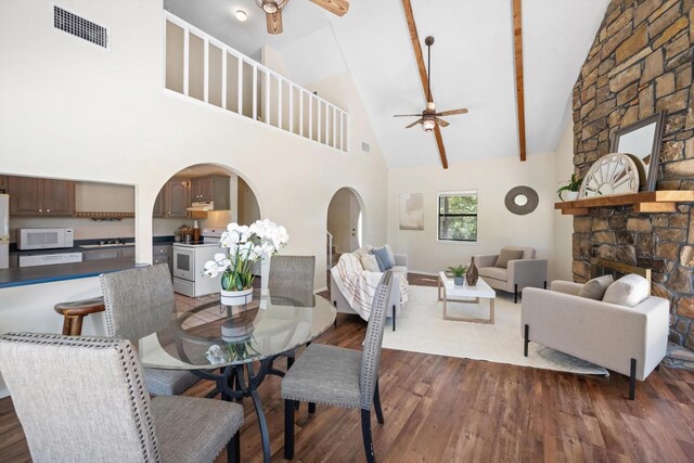 dining area featuring high vaulted ceiling, dark wood-type flooring, a fireplace, and ceiling fan