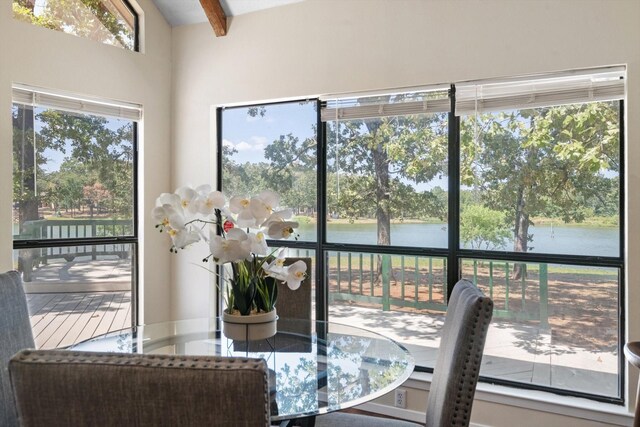 sunroom / solarium featuring beamed ceiling and a water view