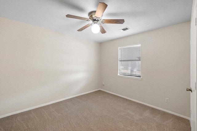 spare room with carpet flooring, baseboards, visible vents, and a ceiling fan