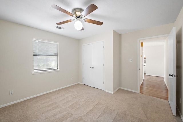 unfurnished bedroom featuring light carpet, ceiling fan, and a closet