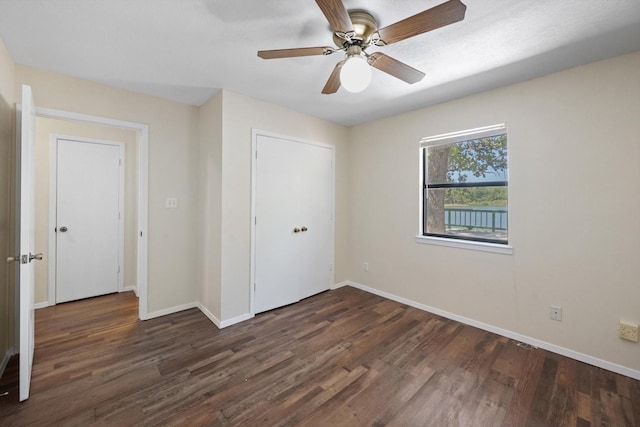 unfurnished bedroom featuring a closet, ceiling fan, baseboards, and dark wood-style flooring