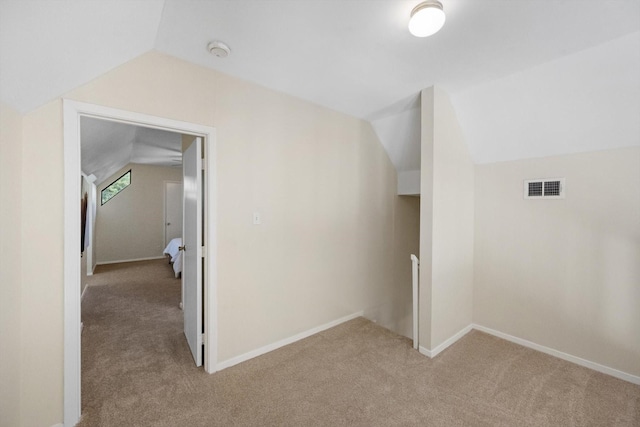 bonus room with lofted ceiling, light colored carpet, visible vents, and baseboards