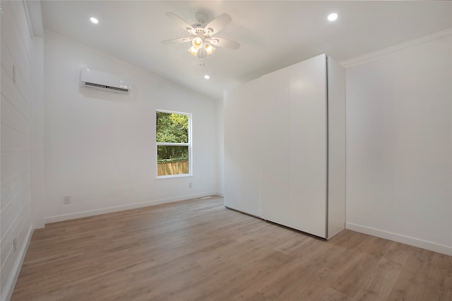 spare room featuring crown molding, vaulted ceiling, light wood-type flooring, ceiling fan, and an AC wall unit