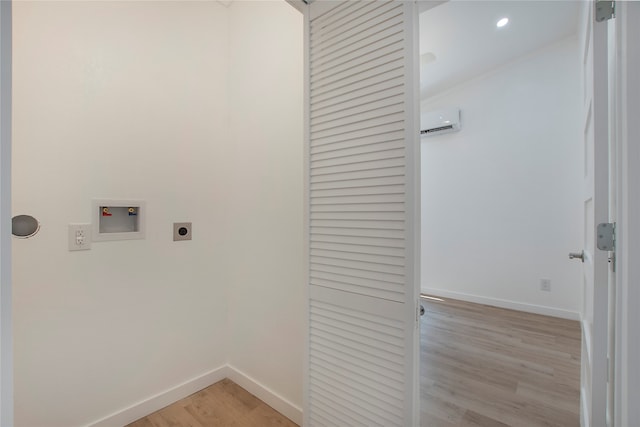 laundry area with a wall mounted air conditioner, hookup for a washing machine, light hardwood / wood-style flooring, and hookup for an electric dryer