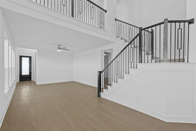 unfurnished living room featuring a high ceiling, hardwood / wood-style flooring, and ceiling fan