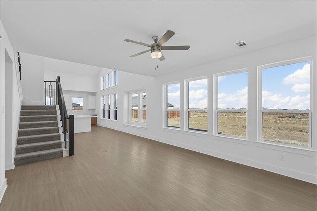 unfurnished living room featuring ceiling fan, plenty of natural light, and dark wood-type flooring