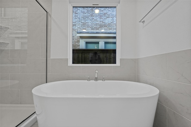 bathroom featuring plus walk in shower and tile walls