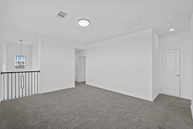 empty room with carpet floors and a notable chandelier