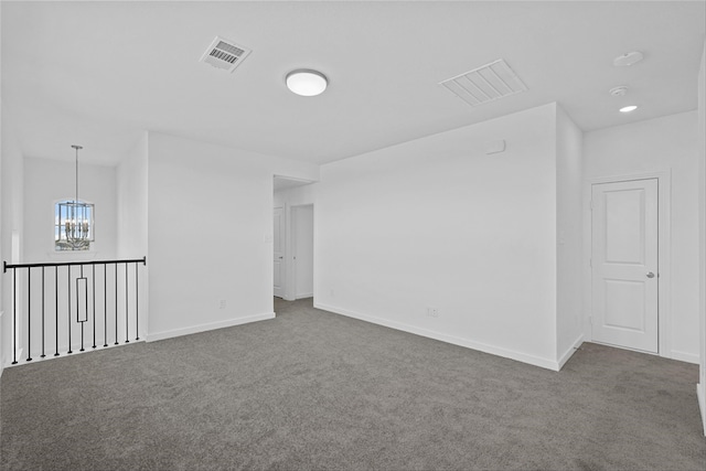 carpeted spare room featuring an inviting chandelier