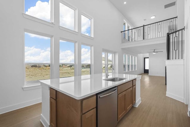 kitchen featuring dishwasher, a towering ceiling, sink, and an island with sink