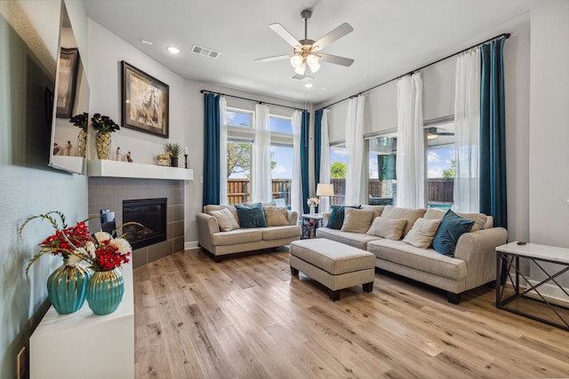 living room with a fireplace, plenty of natural light, light hardwood / wood-style flooring, and ceiling fan