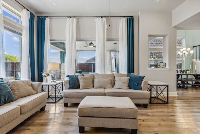 living room featuring ceiling fan with notable chandelier and light wood-type flooring