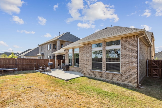 back of property with a yard, a patio area, and a trampoline